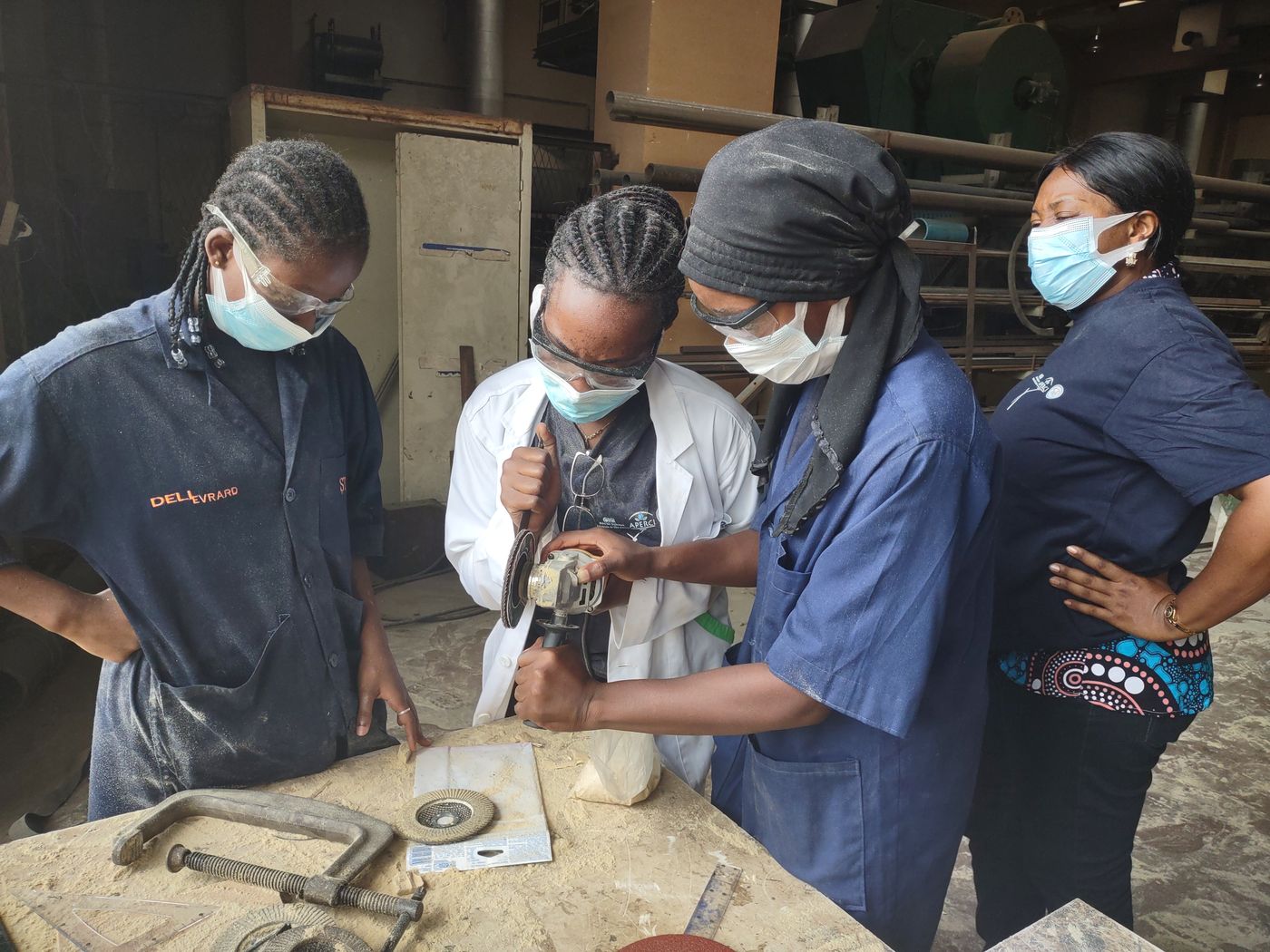 Trainees shaping metal parts at a workbench