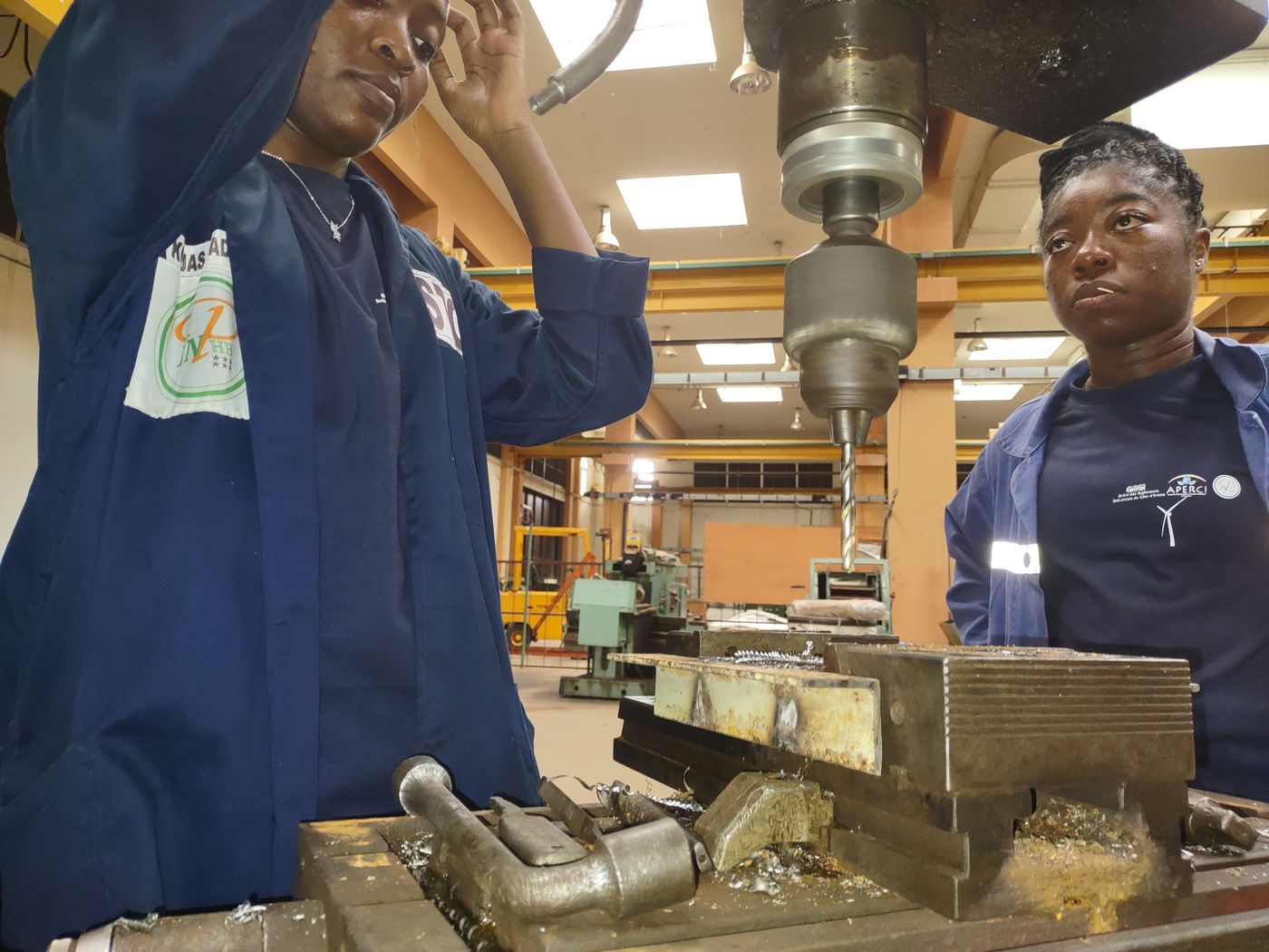 Two trainees working at a drill press