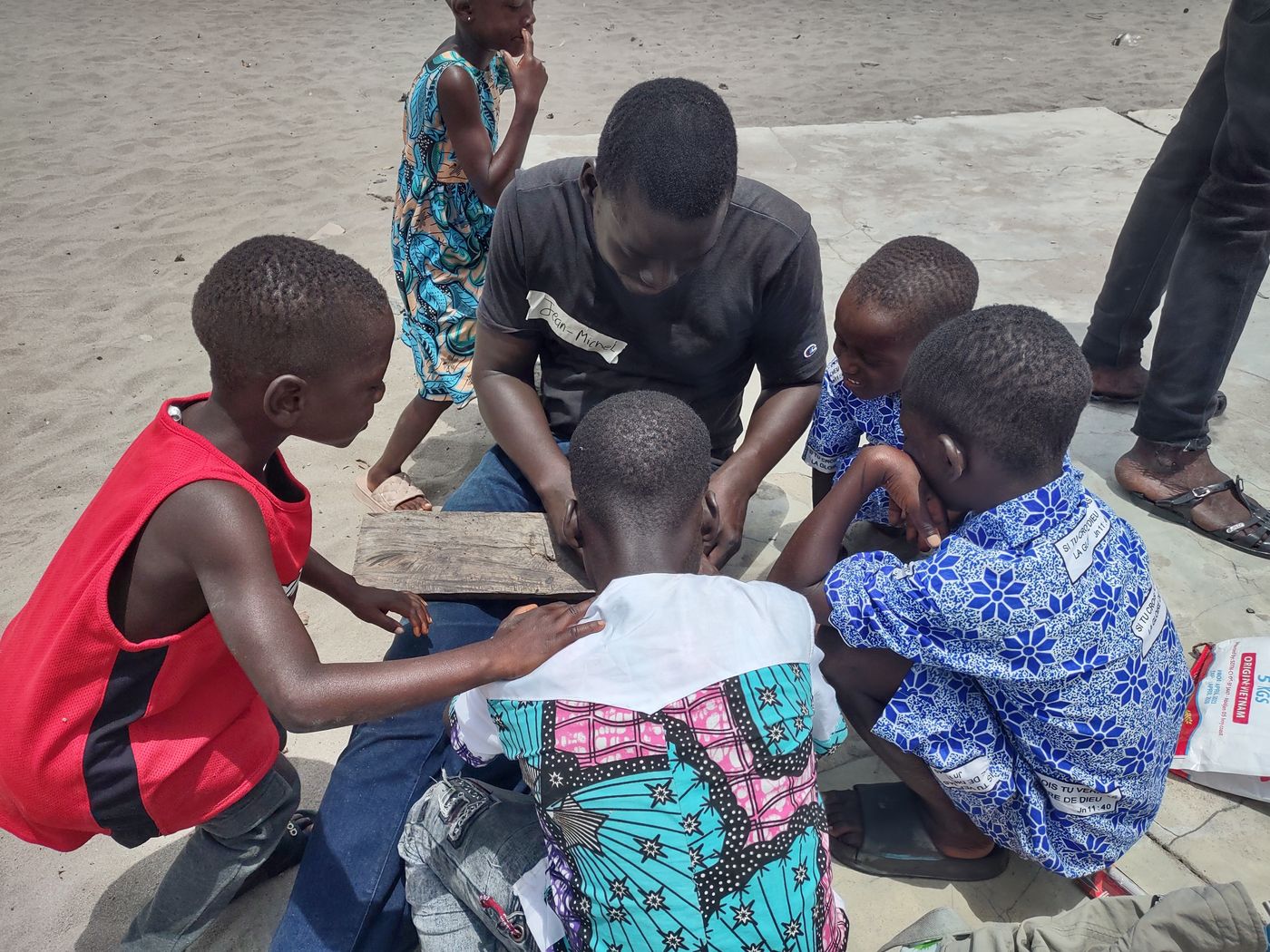 Children gathered around a young man building a small blade